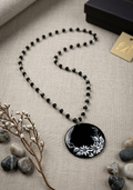 Collana con perline nere sfaccettate e ciondolo nero in porcellana dipinto a mano con fiori bianchi